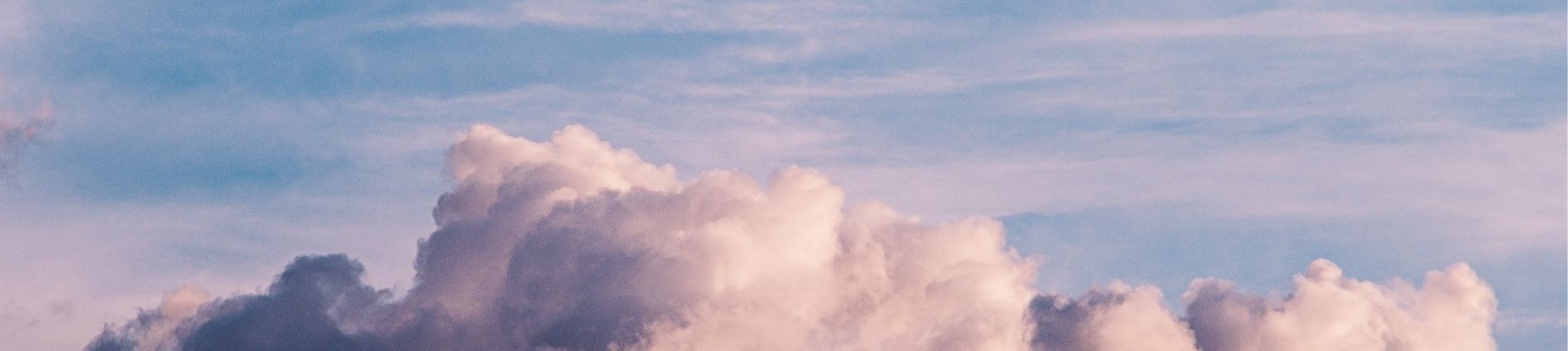 detail van grote zachte wolk in wit-roze tinten tegenover een blauw-roze lucht