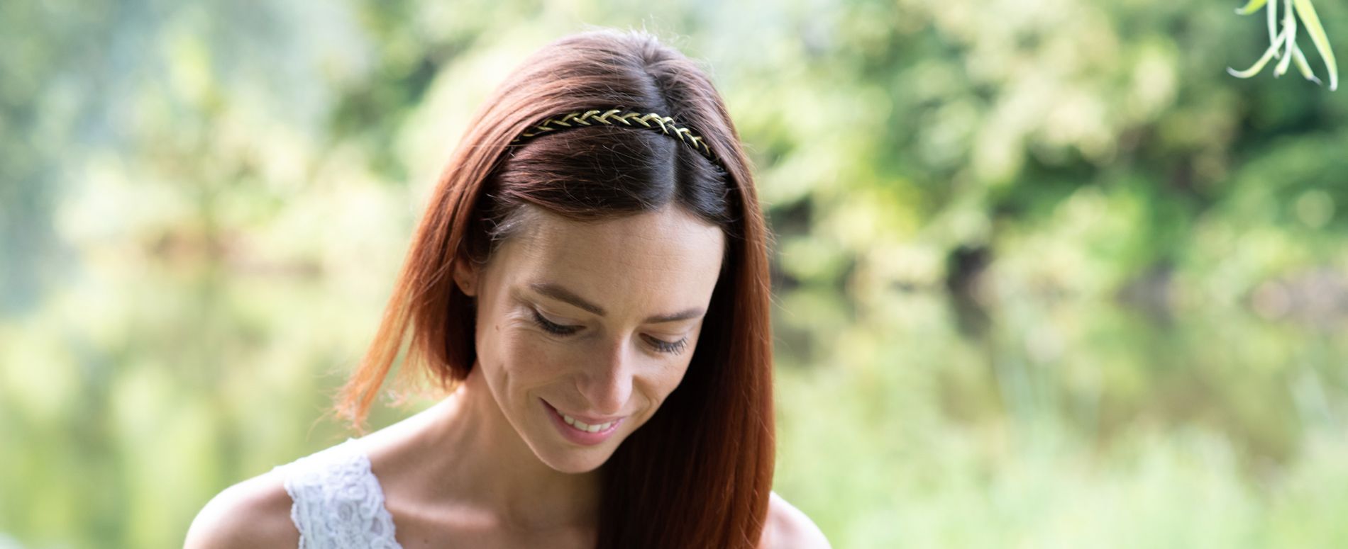 lachend meisje met bruin haar dat omlaag kijkt in de natuur. foto door Bloom Photography